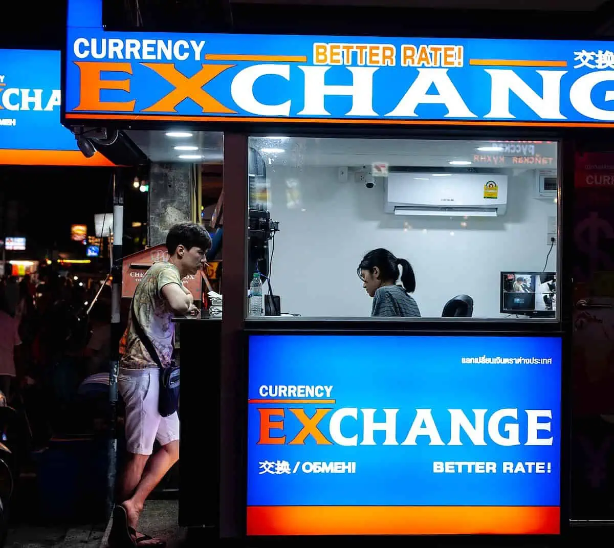 man in gray short standing near counter of currency exchange