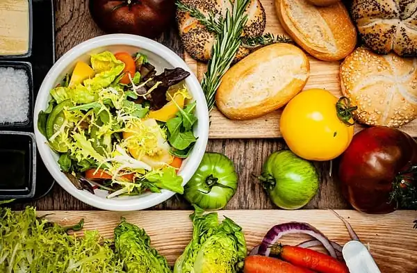 Haitian Bouillon - Meatless vegetable salad on white ceramic bowl beside bread and sliced bread